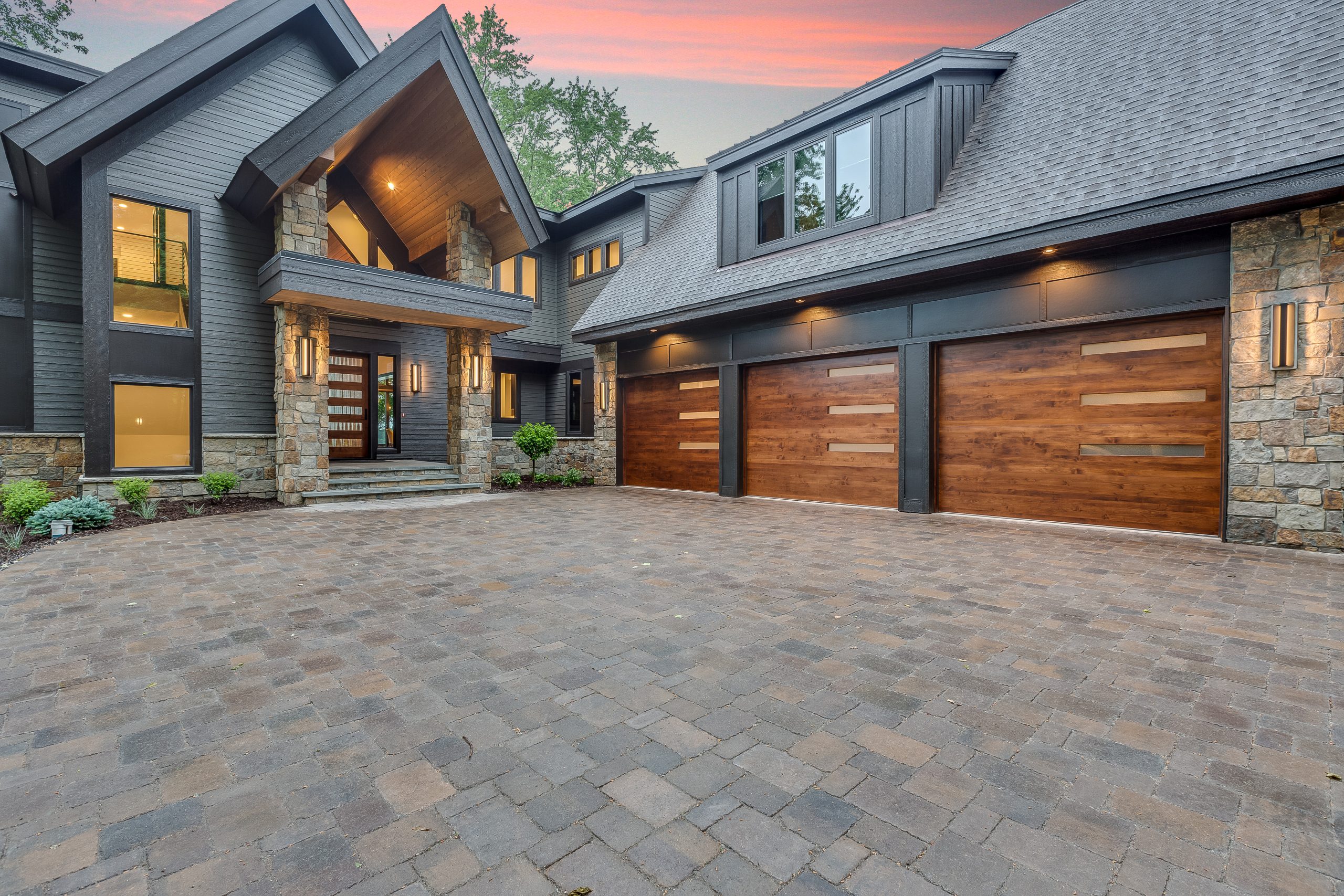 Wood garage door with stone columns Modern style home with amazing front entrance from driveway